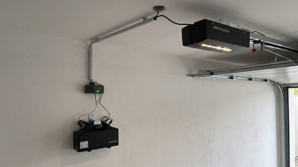 Hörmann ProMatic Akku an der Garagendecke, an der Wand darunter der Laderegler mit grüner Anzeige und der Akkukasten